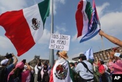 A person holds a sign with a message that reads in Spanish: 'We are all the same Mexico' at an opposition rally called to encourage voting in the upcoming election, in the Zocalo, Mexico City's main square, May 19, 2024.