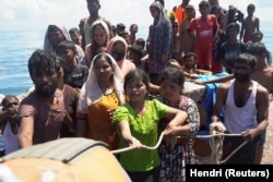 Pengungsi Rohingya memegang tali saat diselamatkan dari perahu yang terbalik di perairan Aceh Barat, 21 Maret 2024. (Foto: REUTERS/Hendri)