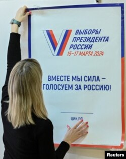 FILE: Seorang anggota KPU setempat menempelkan plakat informasi di dinding sebuah TPS, saat persiapan pemilihan presiden, di Rostov-on-Don, Rusia, 14 Maret 2024. Slogan di plakat itu berbunyi: " Bersama-sama kita adalah kekuatan – pilih Rusia!”. (REUTERS/Sergey Pivovarov)