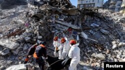 Rescuers carry the body of a victim taken out of the rubble, in the aftermath of the deadly earthquake, in Antakya, Turkey, Feb. 17, 2023.