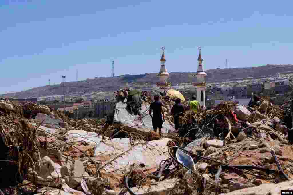People walk amidst the debris, following a powerful storm and heavy rainfall hitting the country, in Derna, Sept.13, 2023.