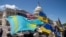 Pengunjuk rasa membawa bendera Kazakstan, AS, dan Ukraina di luar Gedung Kongres AS setelah voting undang-undang yang memberikan bantuan senilai $95 miliar kepada Ukraina, Israel, dan Taiwan. (Foto: REUTERS/Ken Cedeno)
