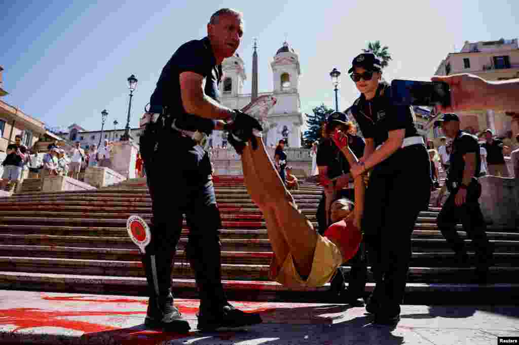 &#39;&#39;Bruciamo tutto&#39;&#39; (Let&#39;s burn everything) activist is removed by police after she poured red paint on the Spanish Steps to protest against femicides in Rome, Italy.