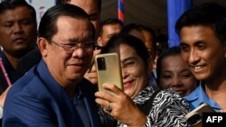 FILE - Cambodia's Prime Minister Hun Sen (L) takes selfies with people during a groundbreaking ceremony for the construction of a 135km expressway from the capital Phnom Penh to Bavet city in Svay Rieng province on the Cambodia-Vietnam border, in Phnom Penh on June 7, 2023.