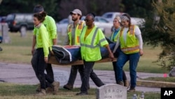 FILE - Researchers and burial oversight committee member Brenda Alford carry the first set of remains exhumed from the latest dig site in Oaklawn Cemetery to an onsite lab for further examination, Sept. 13, 2023, in Tulsa, Okla. 