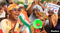 FILE - A person holds a paper that reads 'We no longer want France' as Nigerien women demonstrate in support of the putschists in front of French Army headquarters, in Niamey, Niger, Aug. 30, 2023.