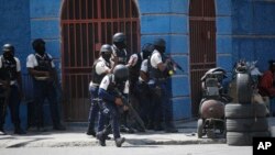 FILE - Police officers take cover during an anti-gang operation in the Lalue neighborhood of Port-au-Prince, Haiti, March 3, 2023. 