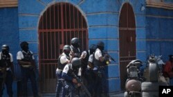 FILE - Police officers take cover during an anti-gang operation in the Lalue neighborhood of Port-au-Prince, Haiti, March 3, 2023. 