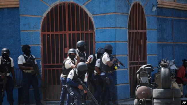 FILE - Police officers take cover during an anti-gang operation in the Lalue neighborhood of Port-au-Prince, Haiti, March 3, 2023.