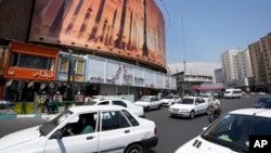 Vehículos en Teherán, Irán, pasan junto a una pancarta antiisraelí que muestra el lanzamiento de misiles, el 19 de abril de 2024. 