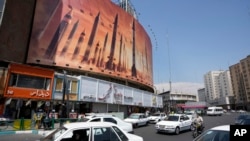 Vehicles in Tehran, Iran, drive past an anti-Israeli banner showing missiles being launched, April 19, 2024. The threat of a wider war between Israel and Iran may give U.S. President Joe Biden more breathing room to provide military assistance to Israel without restrictions.