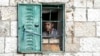 ARCHIVO - Un joven palestino observa desde su ventana una manifestación semanal en solidaridad con los residentes del barrio Sheikh Jarrah en Jerusalén oriental, donde las familias palestinas están bajo amenaza inminente de desplazamiento forzado, el viernes 7 de enero de 2022.