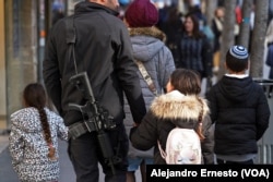 Un hombre pasea por Jerusalén con su familia portando un fusil automático.