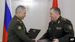 Министр обороны России Сергей Шойгу (слева) и министр обороны Беларуси Виктор Хренин обмениваются документами в Минске, Беларусь, 25 мая 2023 года.