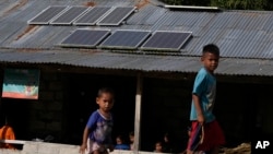 Children play near solar panels installed on the roof of a house in Walatungga village on Sumba Island, Indonesia, March 21, 2023.