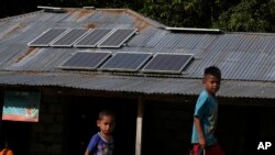 Anak-anak sedang bermain dekat panel surya yang dipasang pada atap sebuah rumah di Desa Walatungga di Pulau Sumba, 21 Maret 2023. (Foto: Dita Alangkara/AP)