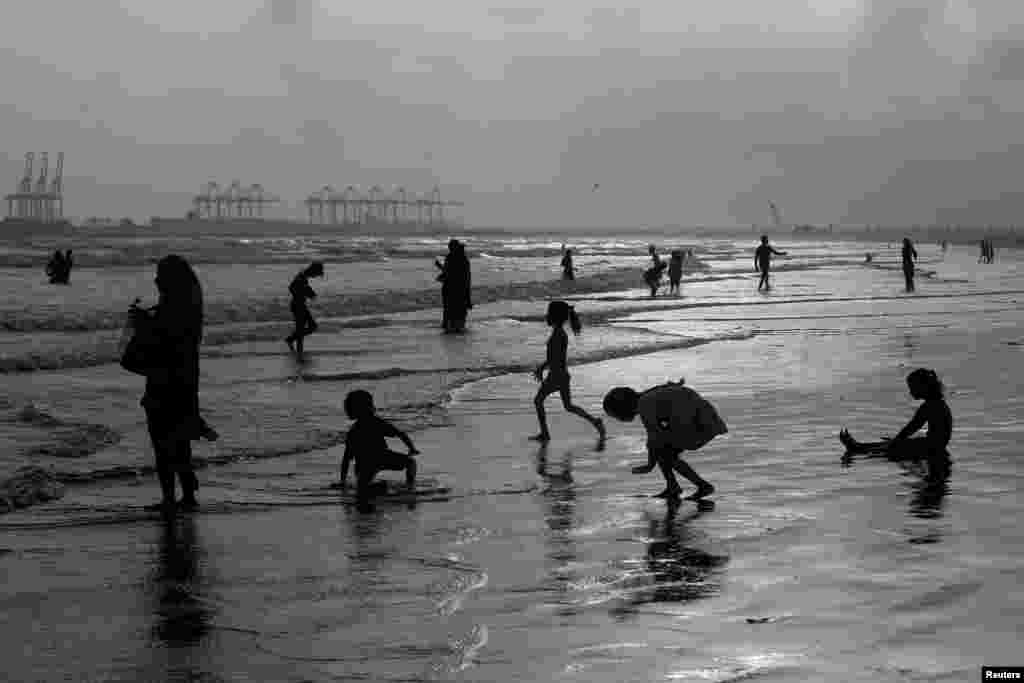 Луѓе, силуета, се разладуваат за време на топол и влажен ден, покрај плажата Клифтон во Карачи, Пакистан.