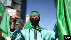 FILE - Demonstrators lift flags of the Palestinian Hamas group during a rally after the Friday prayer in Hebron city in the occupied West Bank on Dec. 15, 2023, protesting Israel's ongoing war against Hamas in Gaza.