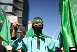 Demonstrators lift flags of the Palestinian Hamas group during a rally Dec. 15, 2023, after the Friday prayer in Hebron city in the occupied West Bank, protesting Israel's ongoing war against Hamas in Gaza.