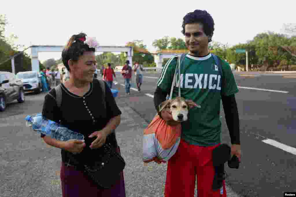 Migrantes cargan a su mascota en su viaje en caravana rumbo a la Ciudad de México.