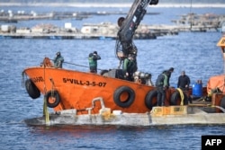 FILE - Spanish Guardia Civil stand as boat crew members tie an alleged narco-submarine before towing it, off Illa de Arousa, in Galicia region, northwestern Spain, on March 14, 2023.