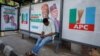 Un homme est assis à un arrêt de bus décoré d'affiches de campagne du candidat à la présidence du All Progressives Congress (APC), Bola Tinubu, avec son colistier Kashim Shettima à Lagos, au Nigeria, le 31 janvier 2023.