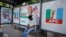 FILE — A man sits at a bus stop decorated with electoral campaign posters of All Progressives Congress Presidential candidate, Bola Tinubu, with his running mate Kashim Shettima, ahead of Nigeria's Presidential election, in Lagos, Jan. 31, 2023.