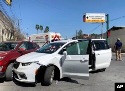 A member of the Mexican security forces stands next to a white minivan with North Carolina plates and several bullet holes, at the crime scene where gunmen kidnapped four U.S. citizens who crossed into Mexico from Texas, March 3, 2023.