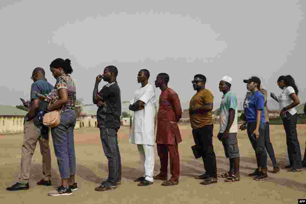 People in line to write their names on a unofficial voters list as they wait for election material to arrive at a polling station in Abuja on February 25, 2023, before polls open during Nigeria&#39;s presidential and general election.