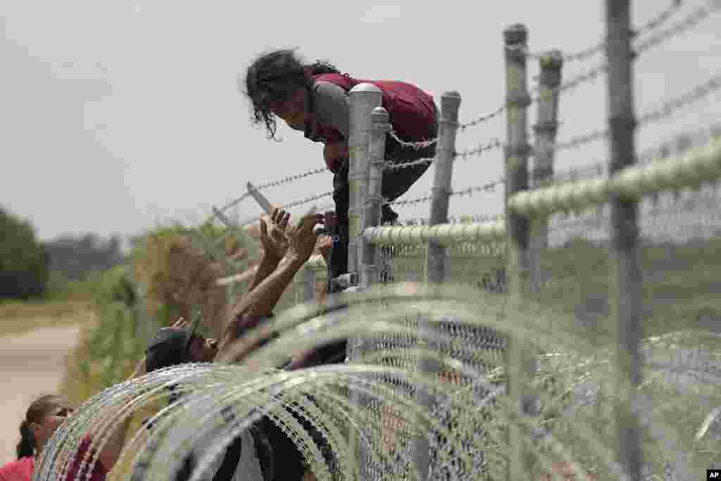 Migrants who crossed the Rio Grande from Mexico into the U.S. climb a fence, Aug. 21, 2023, in Eagle Pass, Texas.