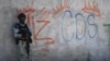 Seorang tentara Meksiko berjaga di samping grafiti pengedar narkoba Mayo Zambada (MZ) dan kelompok kriminal "Cartel de Sinaloa" (CDS), di desa Palmas Altas, kotamadya Jerez de Garcia Salinas, negara bagian Zacatecas, Meksiko, 14 Maret 2022. (Foto: Pedro Pardo/AFP)