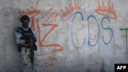 Seorang tentara Meksiko berjaga di samping grafiti pengedar narkoba Mayo Zambada (MZ) dan kelompok kriminal "Cartel de Sinaloa" (CDS), di desa Palmas Altas, kotamadya Jerez de Garcia Salinas, negara bagian Zacatecas, Meksiko, 14 Maret 2022. (Foto: Pedro Pardo/AFP)