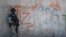 Seorang tentara Meksiko berjaga di samping grafiti pengedar narkoba Mayo Zambada (MZ) dan kelompok kriminal "Cartel de Sinaloa" (CDS), di desa Palmas Altas, kotamadya Jerez de Garcia Salinas, negara bagian Zacatecas, Meksiko, 14 Maret 2022. (Foto: Pedro Pardo/AFP)