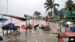A man salvages a cart as water flows on to the Kuakata beach on the coast of Bay of Bengal caused by the advancing Cyclone Remal in Barisal, Bangladesh.