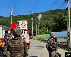 In this photo provided by Jeonbuk Fire Headquarters, balloons with trash presumably sent by North Korea, hang on electric wires as South Korean army soldiers stand guard in Muju, South Korea, May 29, 2024.