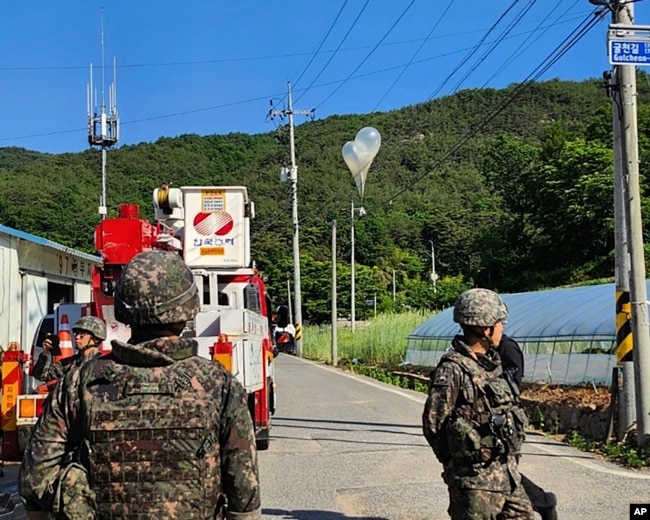 In this photo provided by Jeonbuk Fire Headquarters, balloons with trash presumably sent by North Korea, hang on electric wires as South Korean army soldiers stand guard in Muju, South Korea, May 29, 2024.