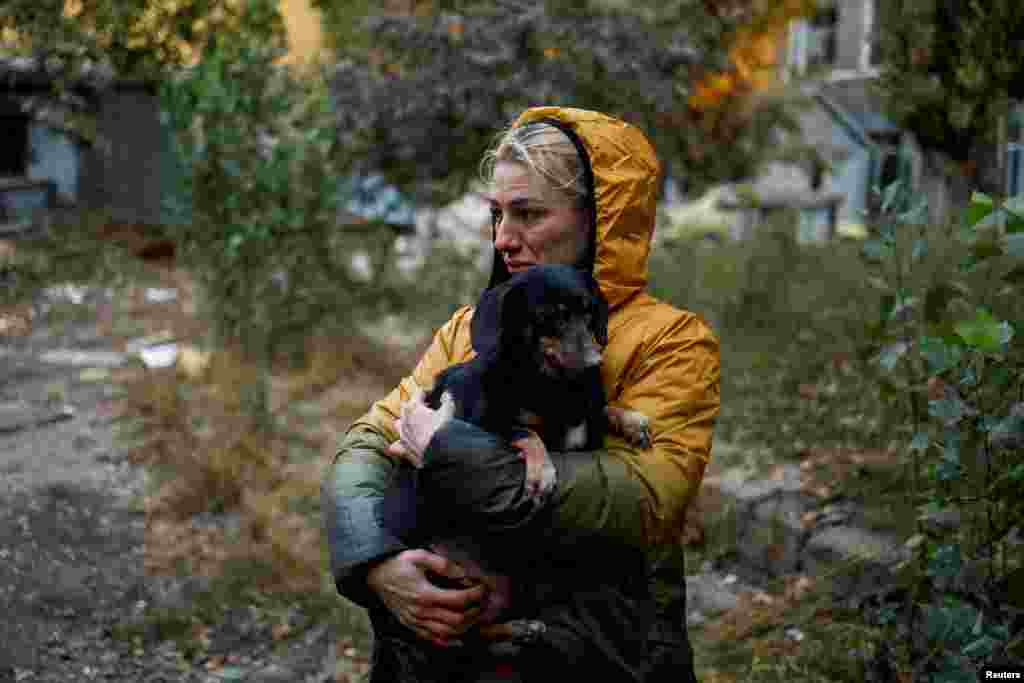 Una vecina carga un perro cerca de un edificio residencial fuertemente dañado por un ataque con misiles rusos el 18 de octubre de 2022.