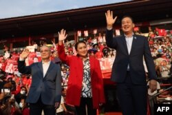 FILE - Thai candidates for prime minister Paetongtarn Shinawatra (C), Srettha Thavisin (R) and Chaikasem Nitisiri (L) wave during a rally for Thailand's main opposition Pheu Thai party at the Thunder Dome Stadium north of Bangkok, April 5, 2023.