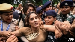 Indian wrestler Vinesh Phogat (C) is detained by the police during a protest against Brij Bhushan Singh, the wrestling federation chief, in New Delhi on May 28, 2023.
