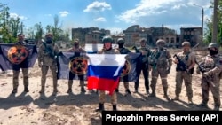 In this handout photo taken from video and released by Prigozhin Press Service, May 20, 2023, Yevgeny Prigozhin, the head of the Wagner Group military company holds a Russian national flag in Bakhmut, Ukraine. (Prigozhin Press Service/AP)