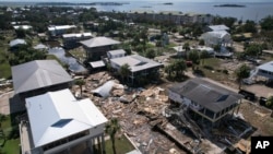 In this photo taken with a drone, debris from homes swept off their lots chokes a canal amid homes on stilts which remain standing, in Horseshoe Beach, Florida, Aug. 31, 2023, one day after the passage of Hurricane Idalia.