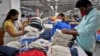 资料照片: 2022年2月9日印度一家纺织厂工人在包装T 恤前进行质量检查