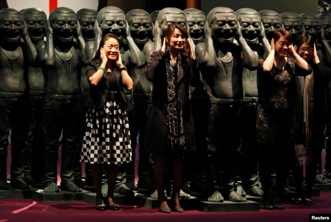 香港苏富比拍卖中国艺术家岳敏君的作品前观众与他的作品合影。（2011年3月31日）