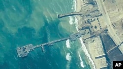 FILE - The image provided by U.S. Central Command, shows U.S. Army soldiers, U.S. Navy sailors and Israel Defense Forces placing the Trident Pier on the coast of the Gaza Strip, on May 16, 2024.