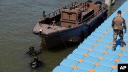 Military divers emerge from the water after inspecting a boat on the Seine river in Paris, July 17, 2024.