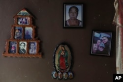 An Our Lady of Guadalupe wooden plaque and family photos adorn a wall in the home of Fabricio Chicas, a transgender man, in San Salvador, El Salvador, April 30, 2023.