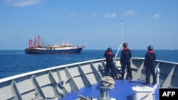 FILE - This handout photo taken April 27, 2021 and received from the Philippine coast guard on May 5, 2021 shows Philippine coast guard personnel aboard their ship BRP Cabra monitoring Chinese vessels anchored at Sabina Shoal, in the South China Sea. 