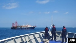 FILE - This handout photo taken Apr. 27, 2021 and received from the Philippine coast guard shows Philippine coast guard personnel aboard their ship BRP Cabra monitoring Chinese vessels anchored at Sabina Shoal, in the South China Sea. 