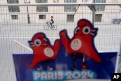 A cyclist rides in an empty street outside the security perimeter set up for the Olympic Games in Paris, July 18, 2024.