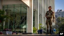 An armed security person stands stand guard at the gate of a building housing BBC office in New Delhi, India, Feb. 15, 2023.